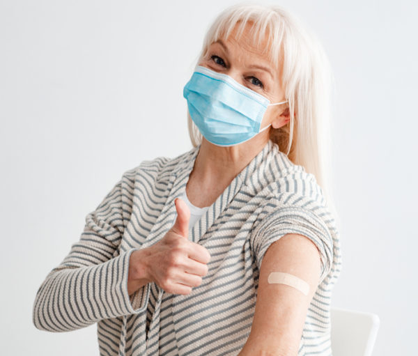 Senior woman with facemask giving thumbs up sign
